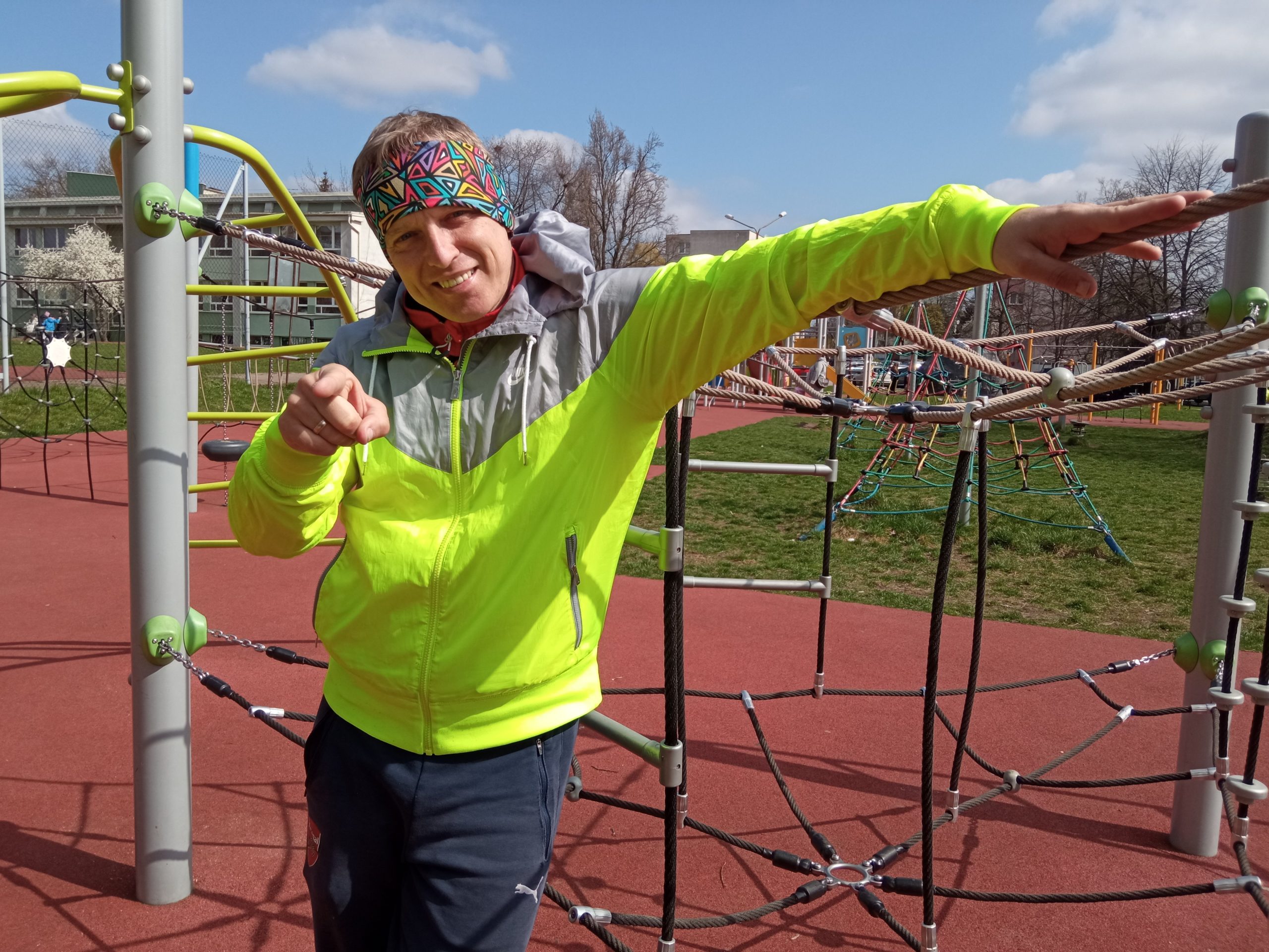 Mężczyzna w sportowym stroju stoi przy sportowych urządzeniach na szkolnym boisku