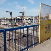 Kładka nad torami, w tle semafory, pociągi na peronach i budynek dworca