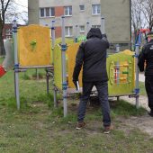 Dwóch mężczyzn, w tym jeden to funkcjonariusz Straży Miejskiej stoją przy placu zabaw.