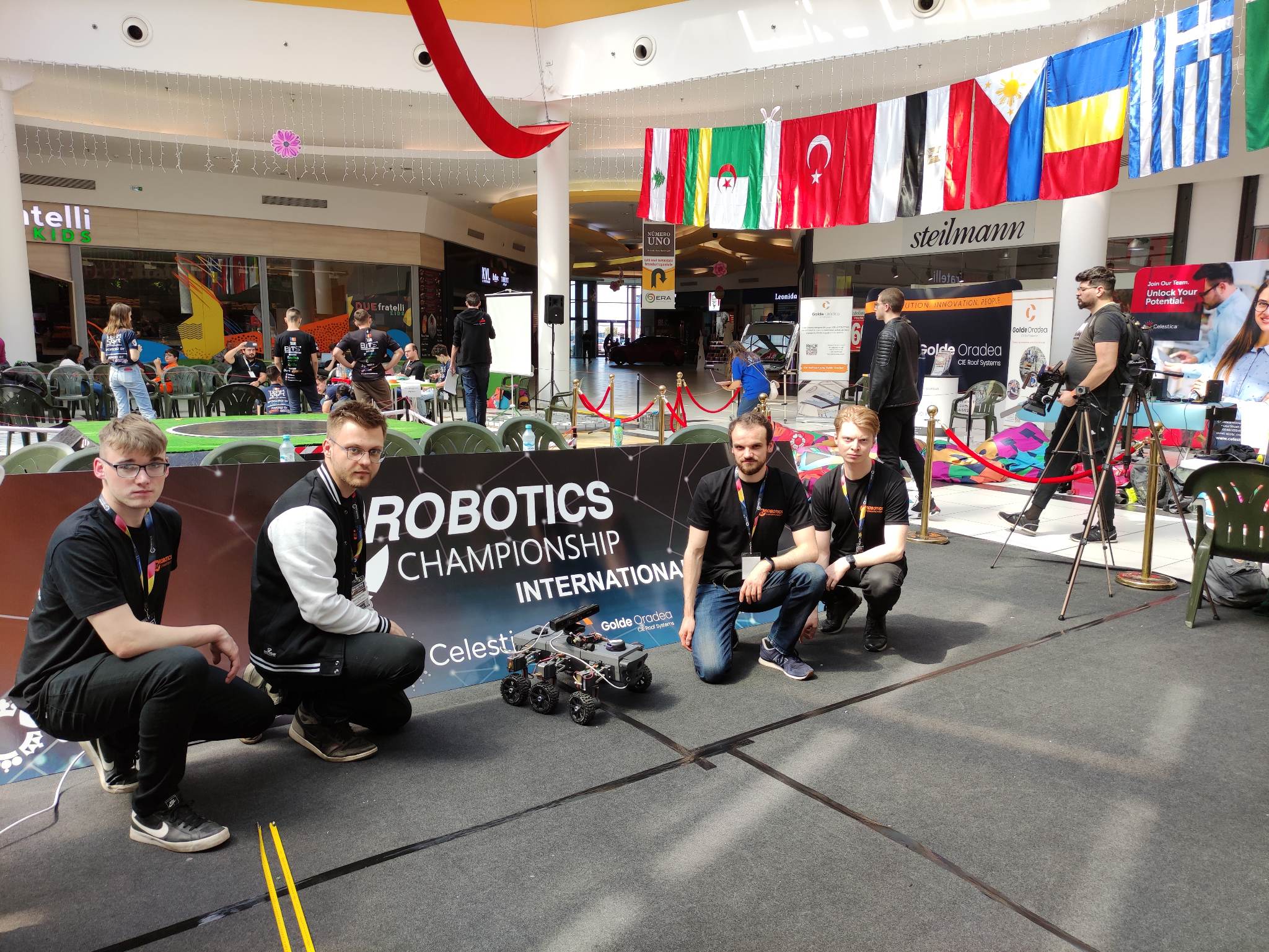 Czterech młodych mężczyzn prezentuje swój projekt na zawodach robotyków