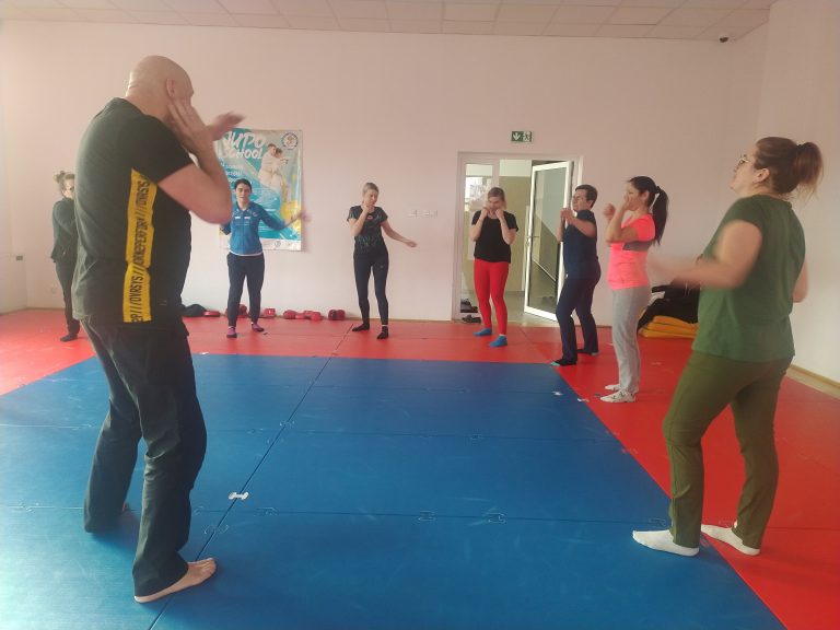 Mężczyzna, a w tle kobiety ćwiczą na sali sportowej