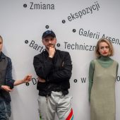 Ludzie stoją pod ścianą w trakcie wernisażu wystawy