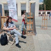 Na Rynku Kościuszki jedna dziewczyna siedzi i rysuje pokaz tańca, druga maluje na sztalugach