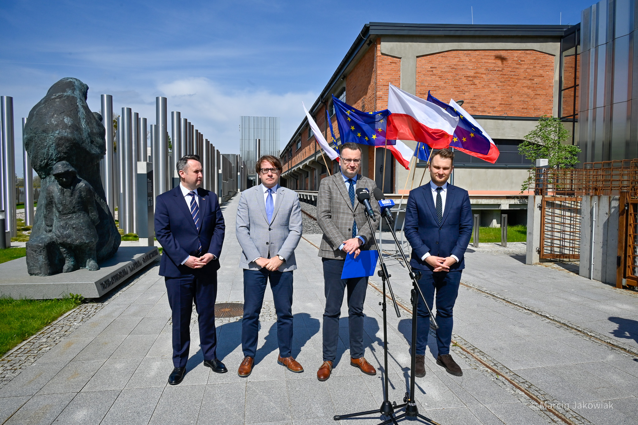 Czterech mężczyzn w garniturach stoi przed wejściem do Muzeum Pamięci Sybiru.