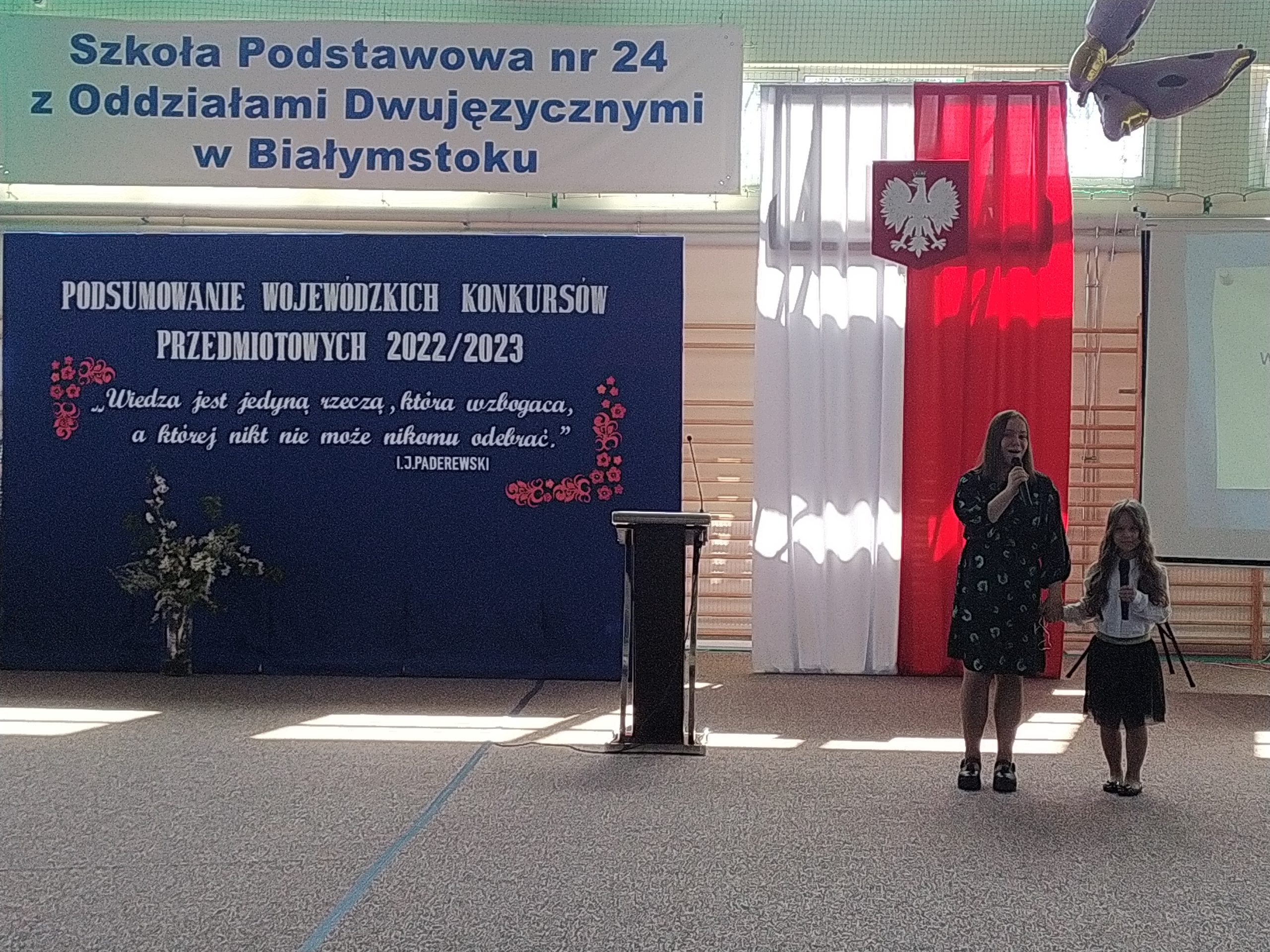 Dwie dziewczynki stoją na apelu szkolnym.