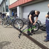 Dwóch uczniów w roboczych ubraniach naprawia rower.
