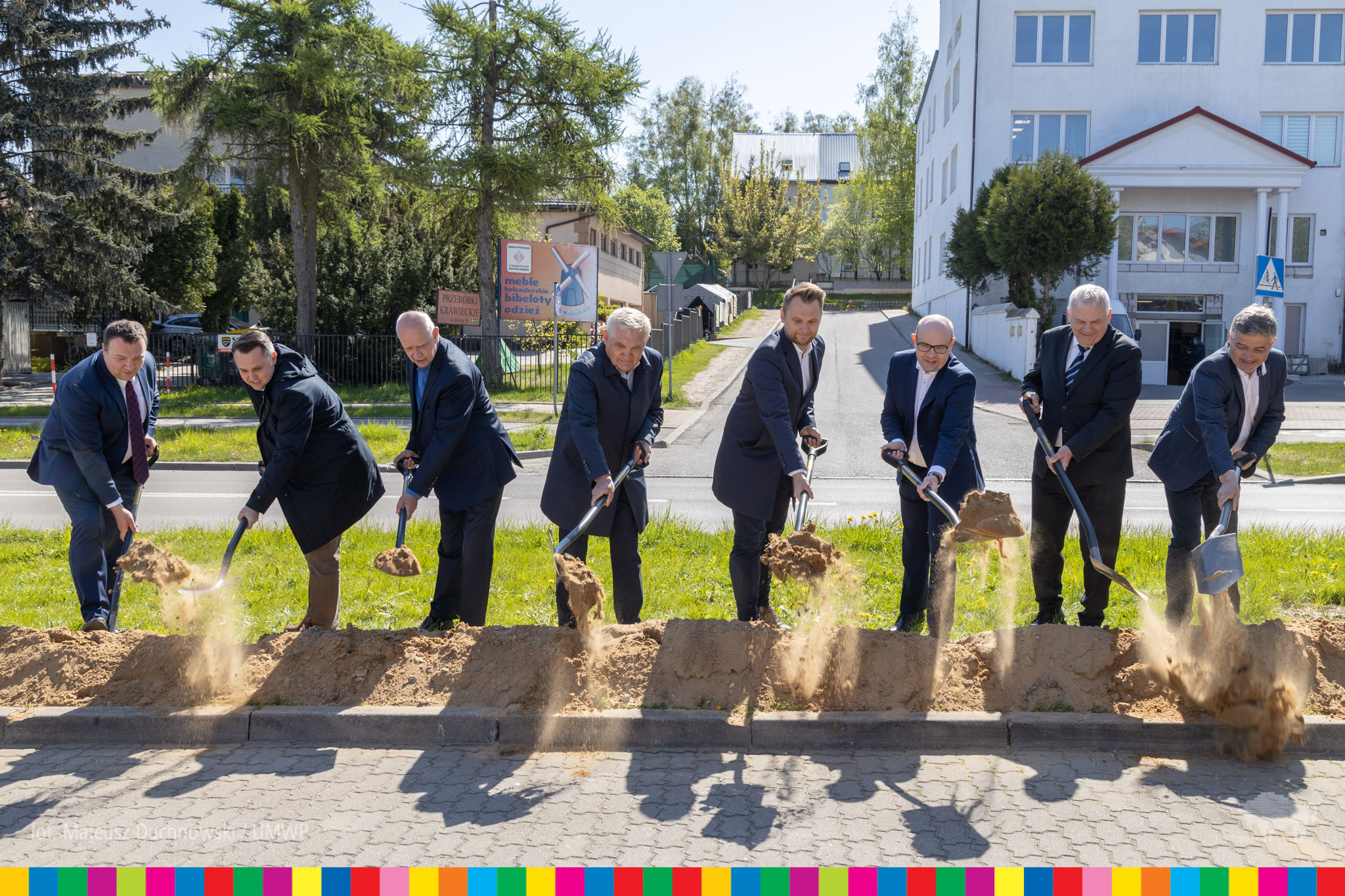 Kilku mężczyzn wbija łopaty w ziemię wzdłuż chodnika