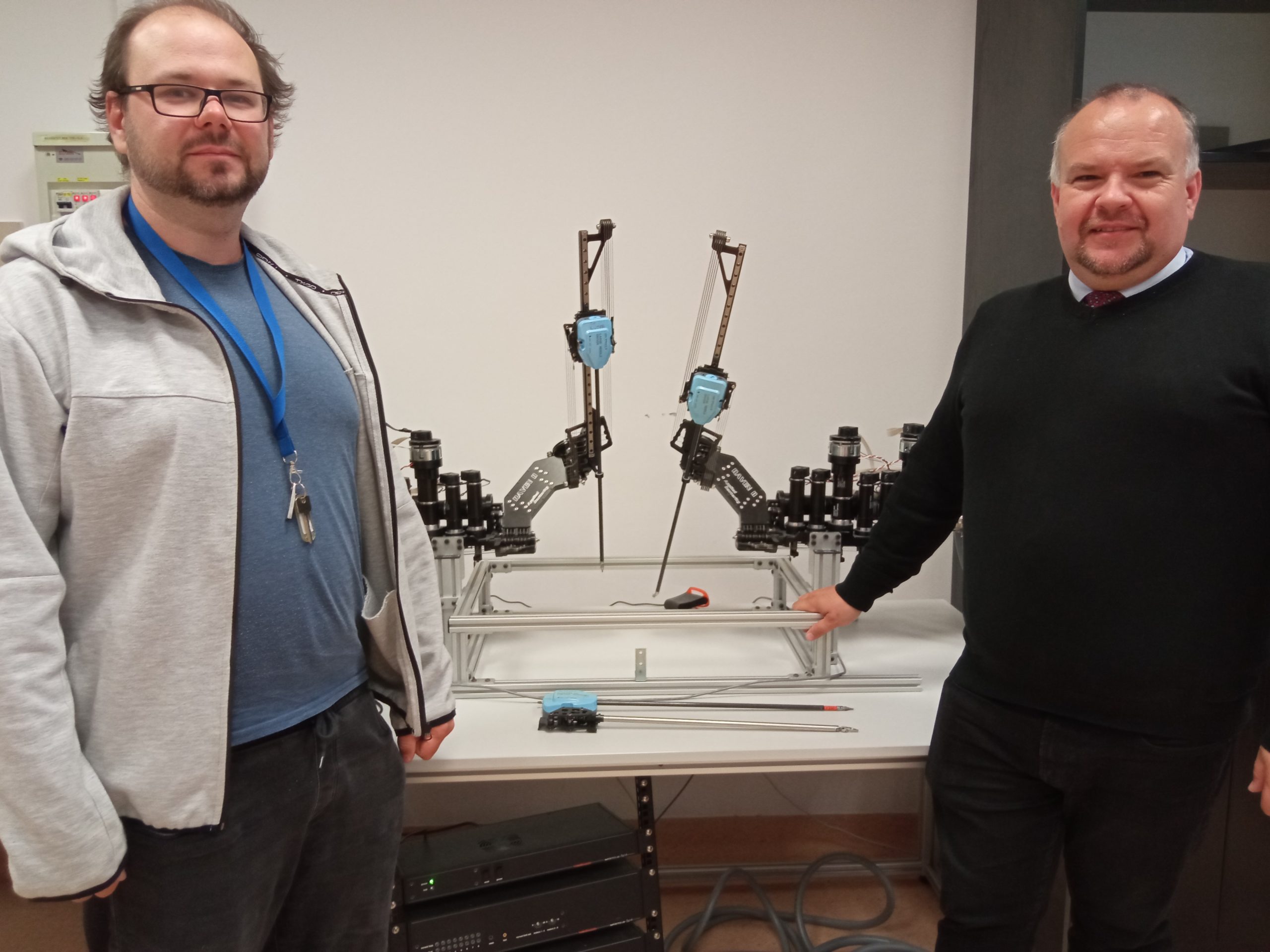 Mężczyźni stoja przy stole, na którym ustawiony jest robot
