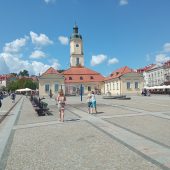 Ludzie spacerują po Rynku; w tle ratusz