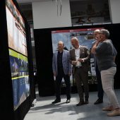 Ludzie patrzą na wizualizacje i projekty na ścianie.
