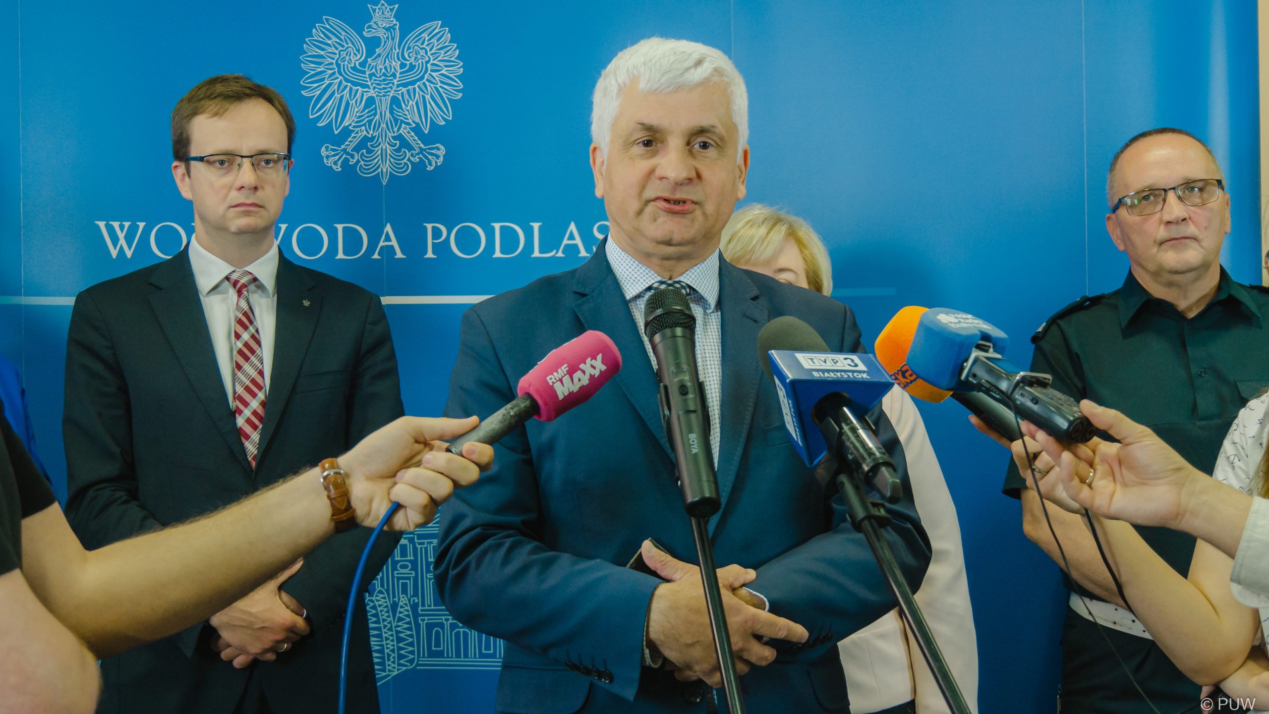Mężczyzna mówi do mikrofonów dziennikarzy,