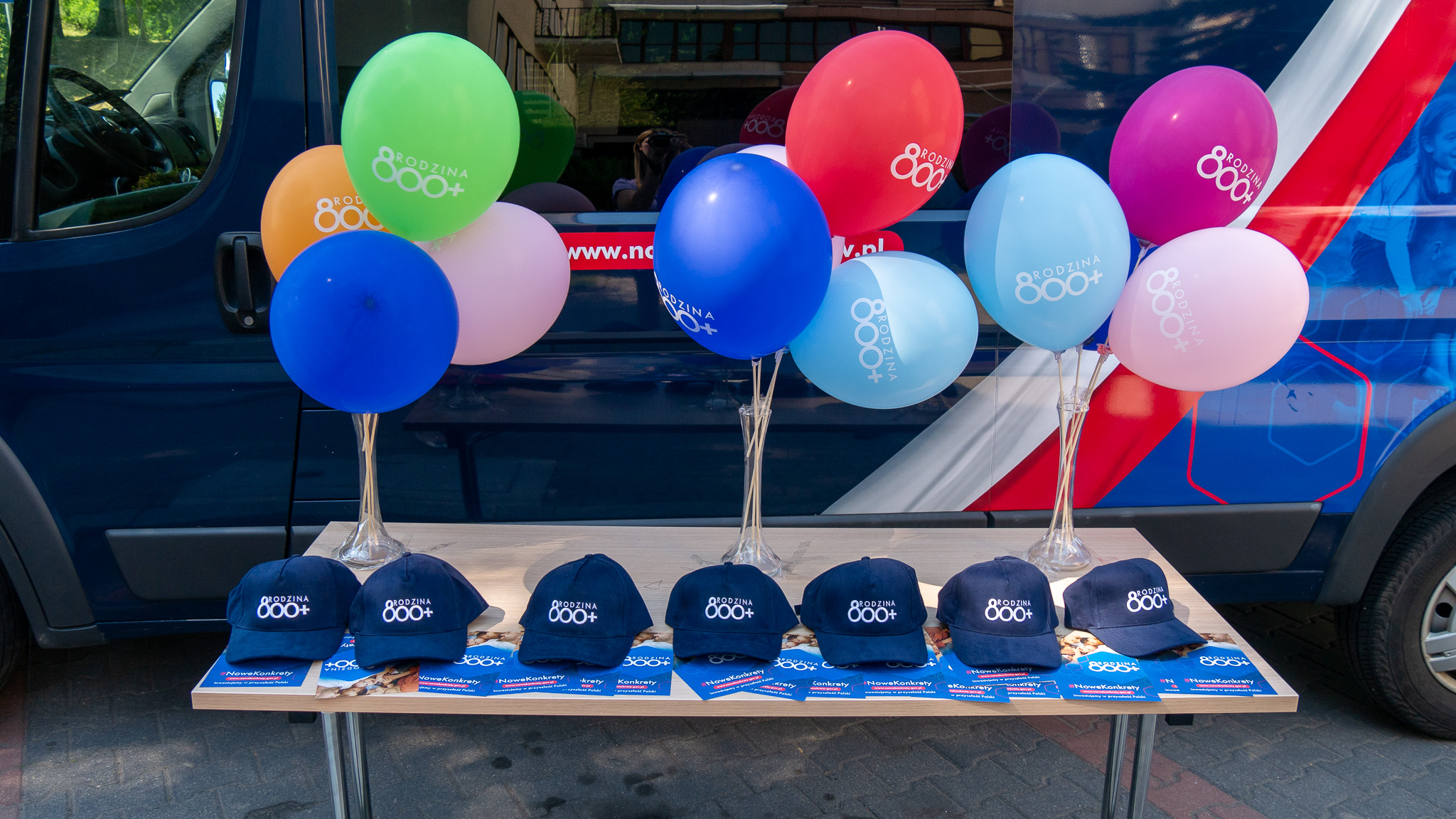 Balony i czapeczki promocyjne leżą na stole.