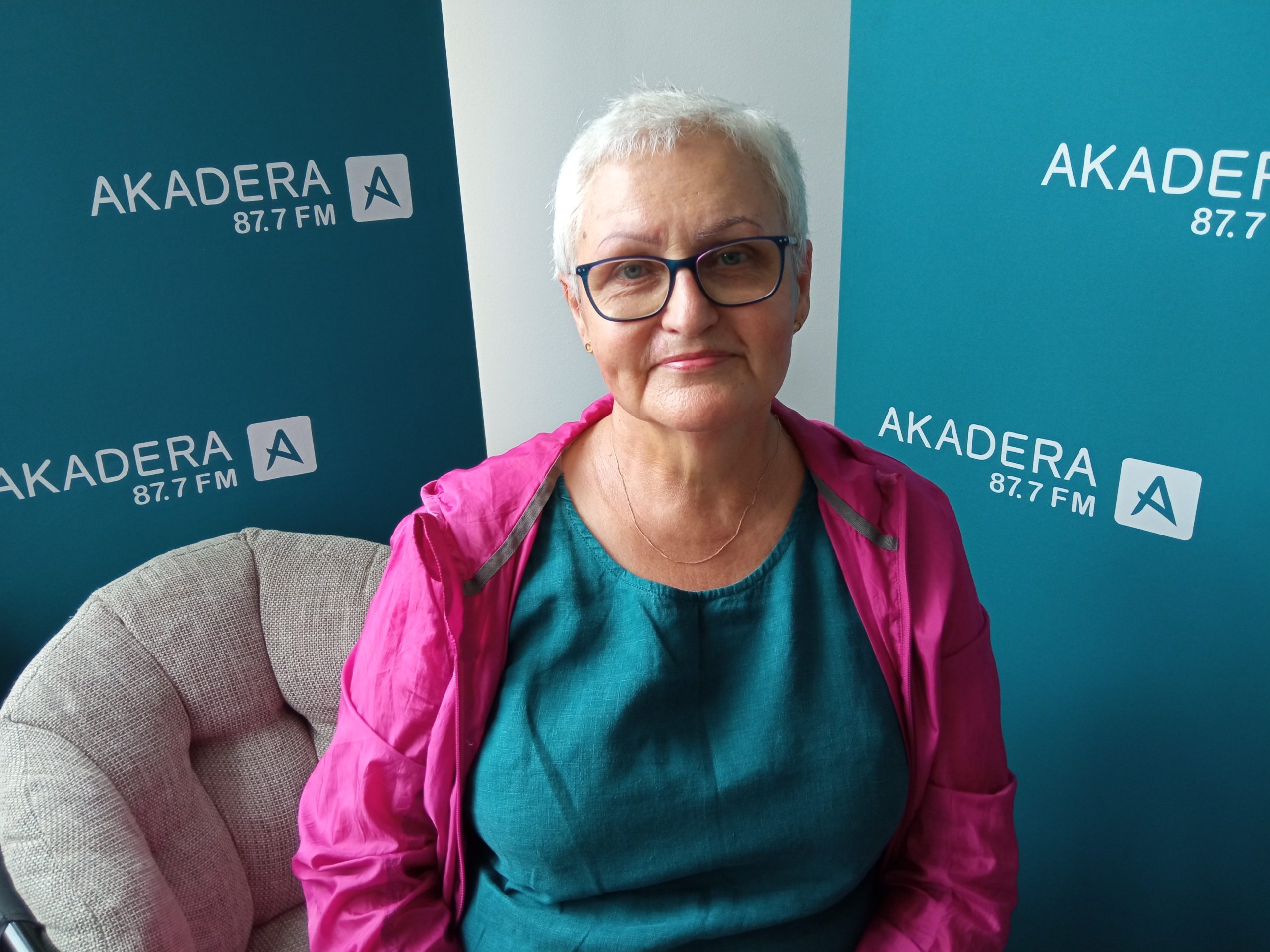Kobieta siedzi na tle banerów radia akadera