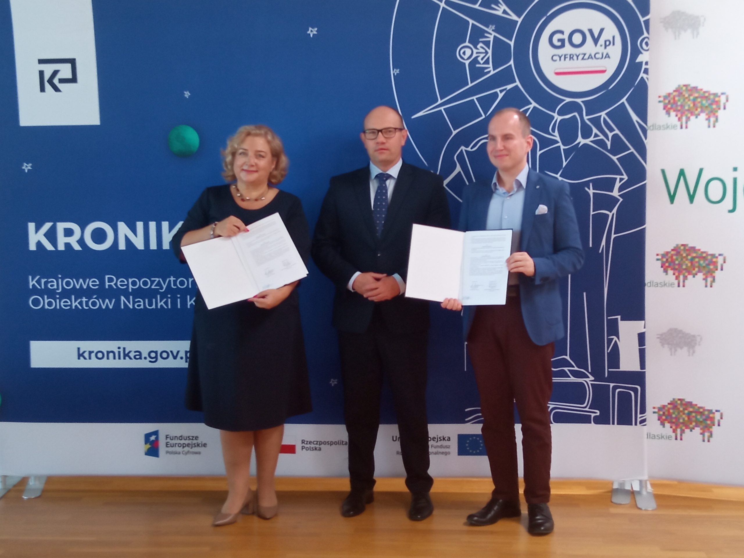 Kobieta i dwaj mężczyźni orezentują podpisane porozumienie