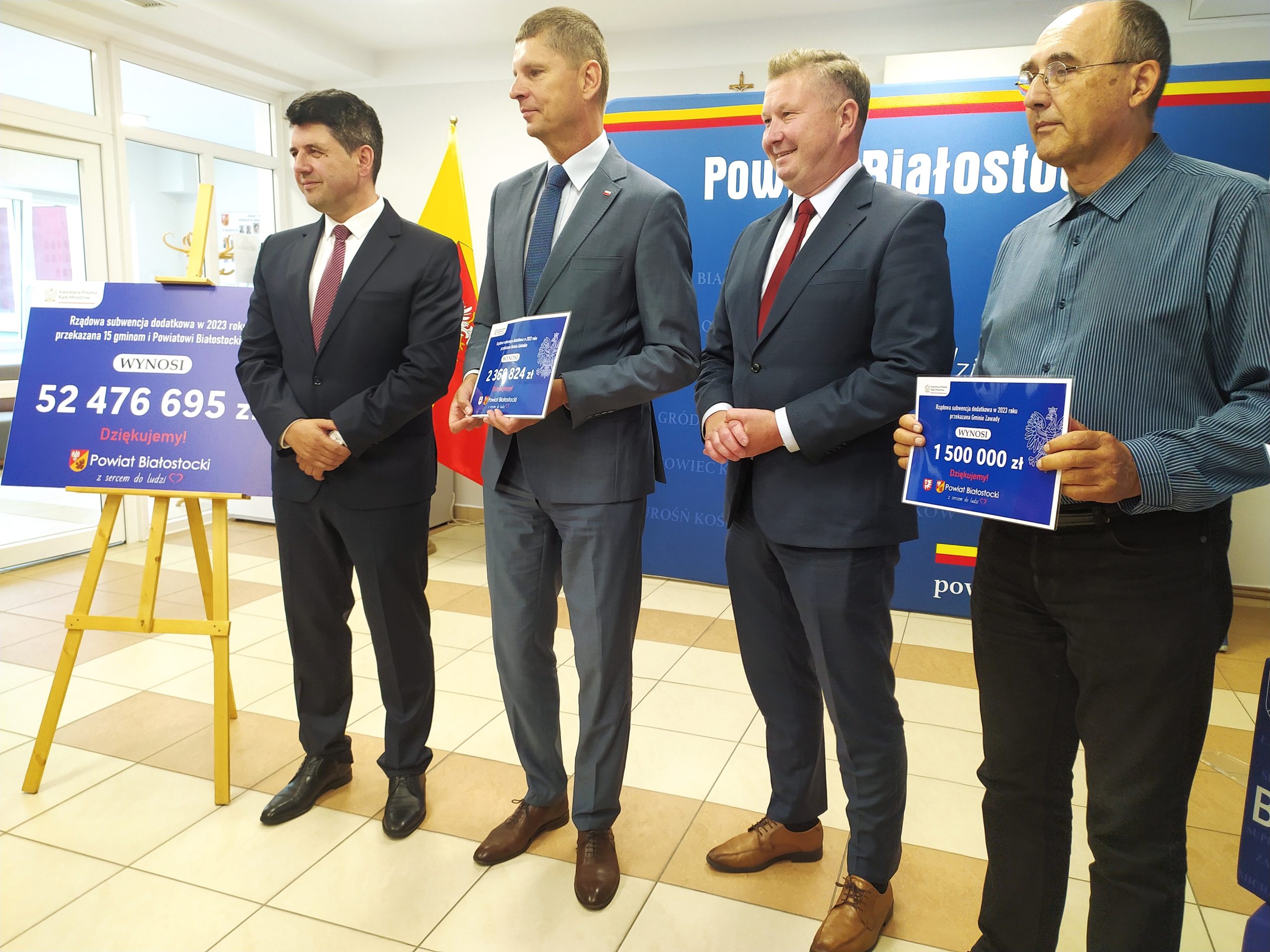 czterech mężczyzn pozuje do zdjęcia z czekami w rękach.