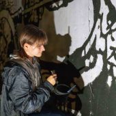 Chłopak maluje mural.