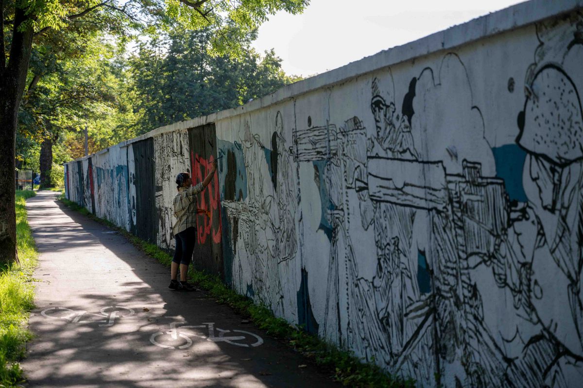 Chłopak maluje mural.