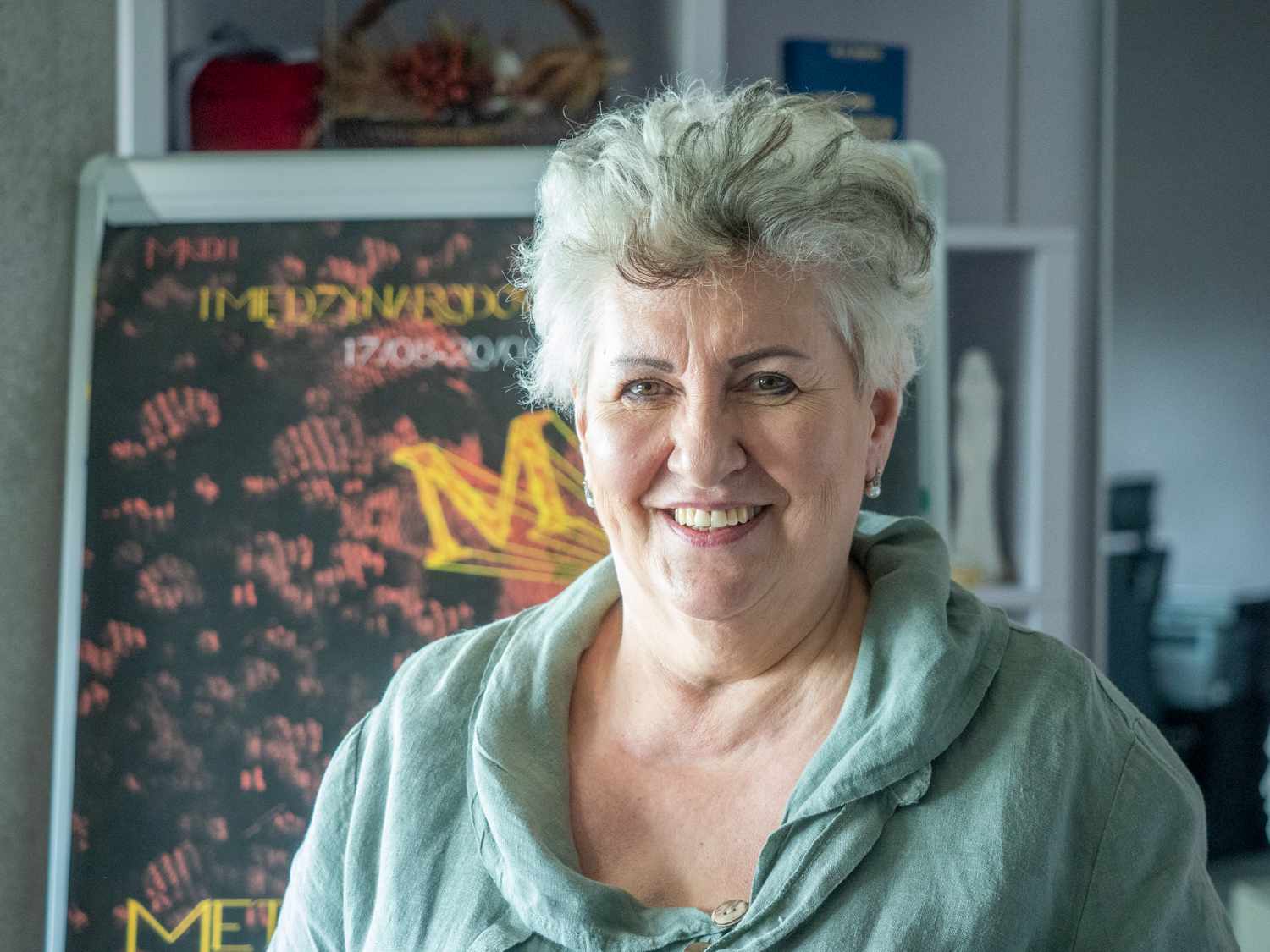 Siwa kobieta na tle obrazów.