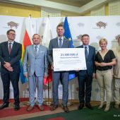 Sześć osób pozuje do zdjęcia na tle baneru oraz z tabliczką z napisem o wysokości dotacji