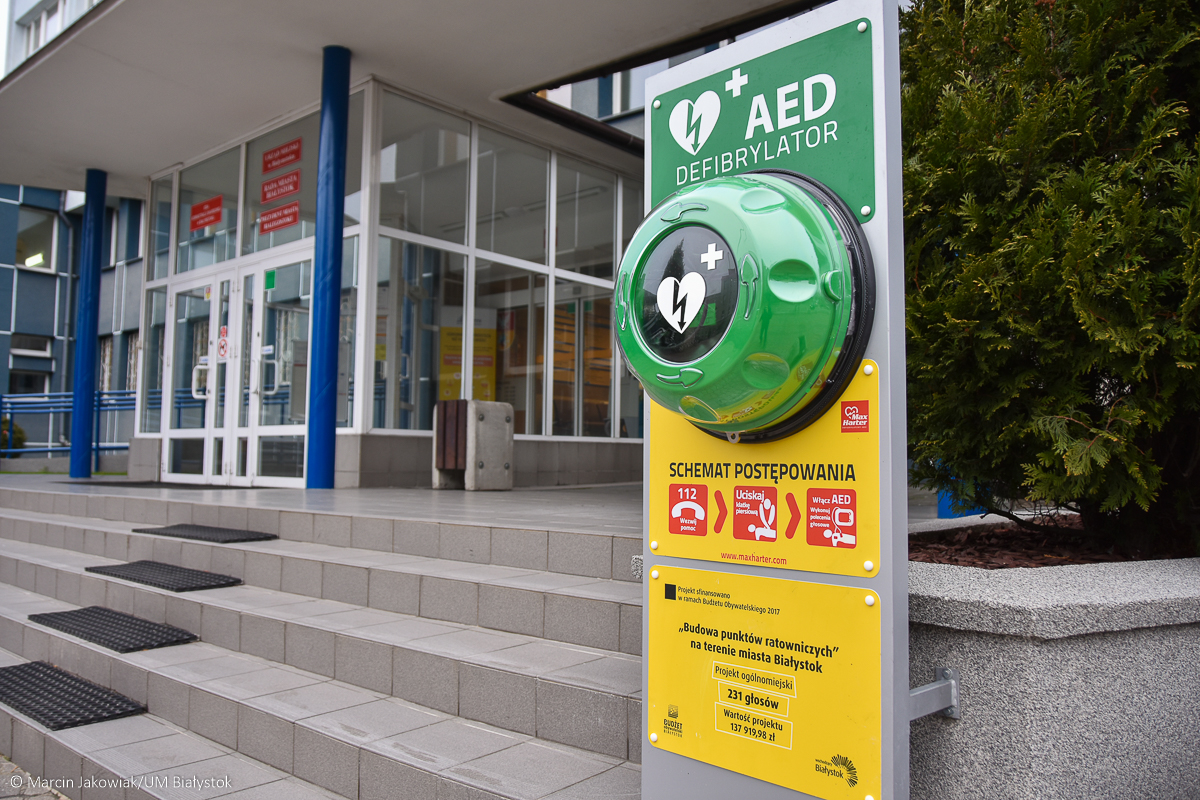 Defibrylator w zielonej kopule przed budynkiem.