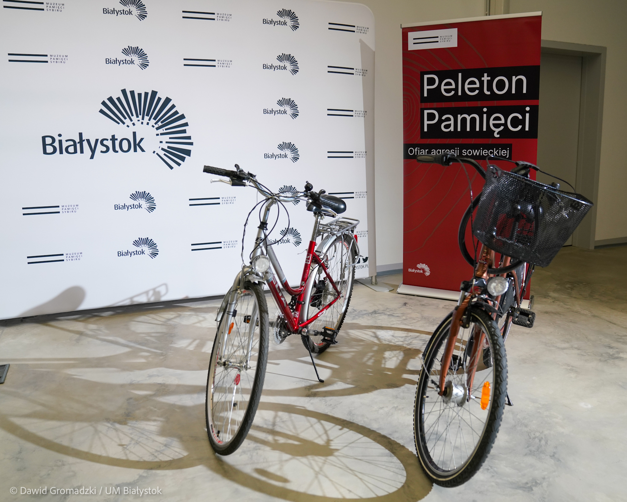 Dwa rowery stoją na tle napisu peleton pamięci