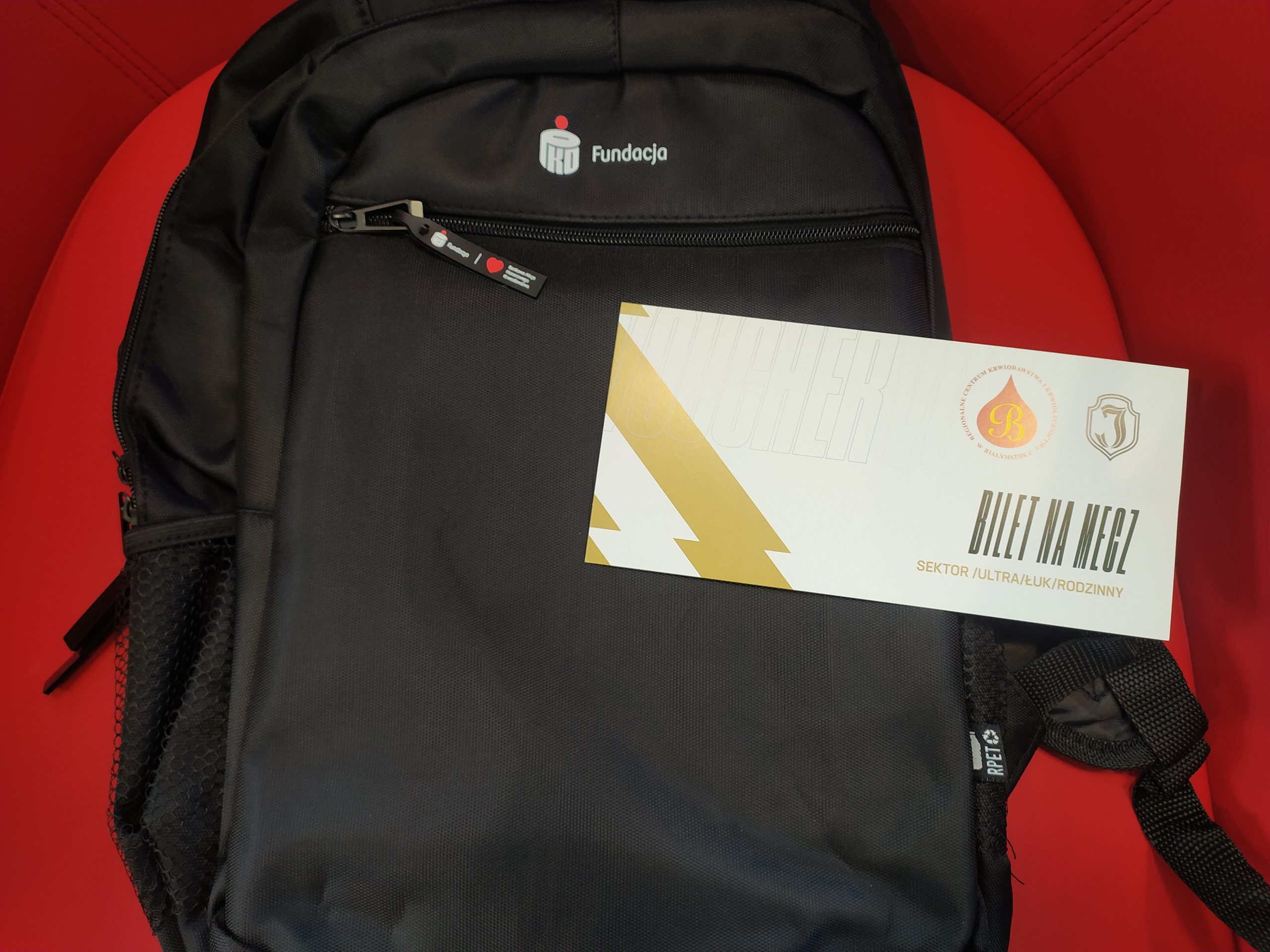Na plecaku leży voucher na mecz piłkarski.