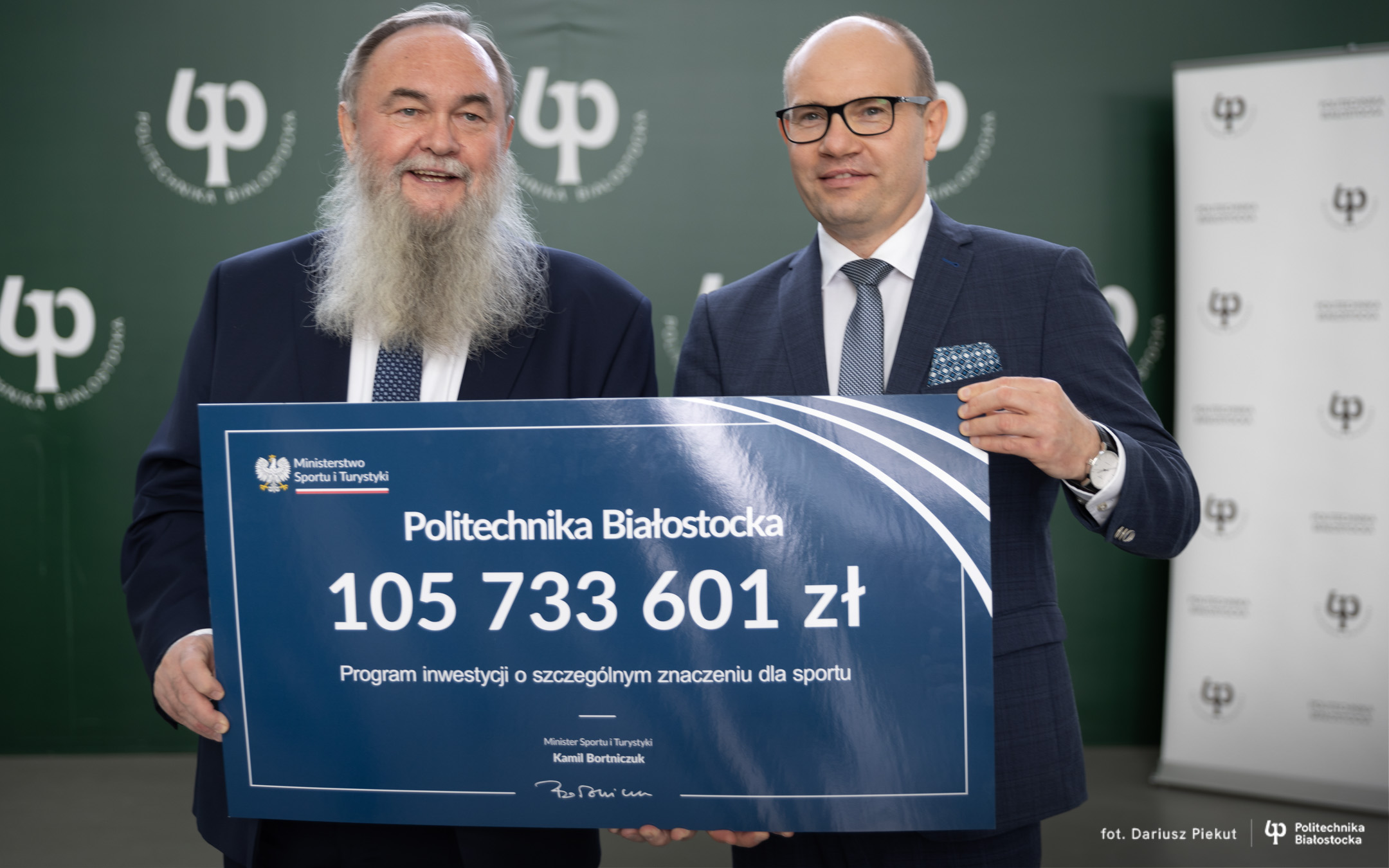 Dwóch mężczyzn trzyma tabliczkę - symboliczny czek z kwotą dofinansowania
