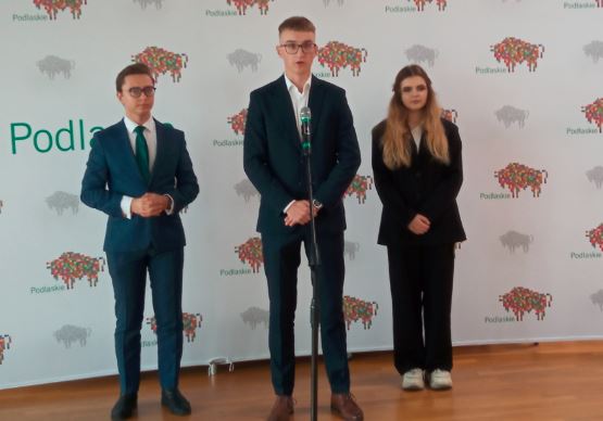 Dwóch młodych mężczyzn i jedna kobieta stoją przy mikrofonie