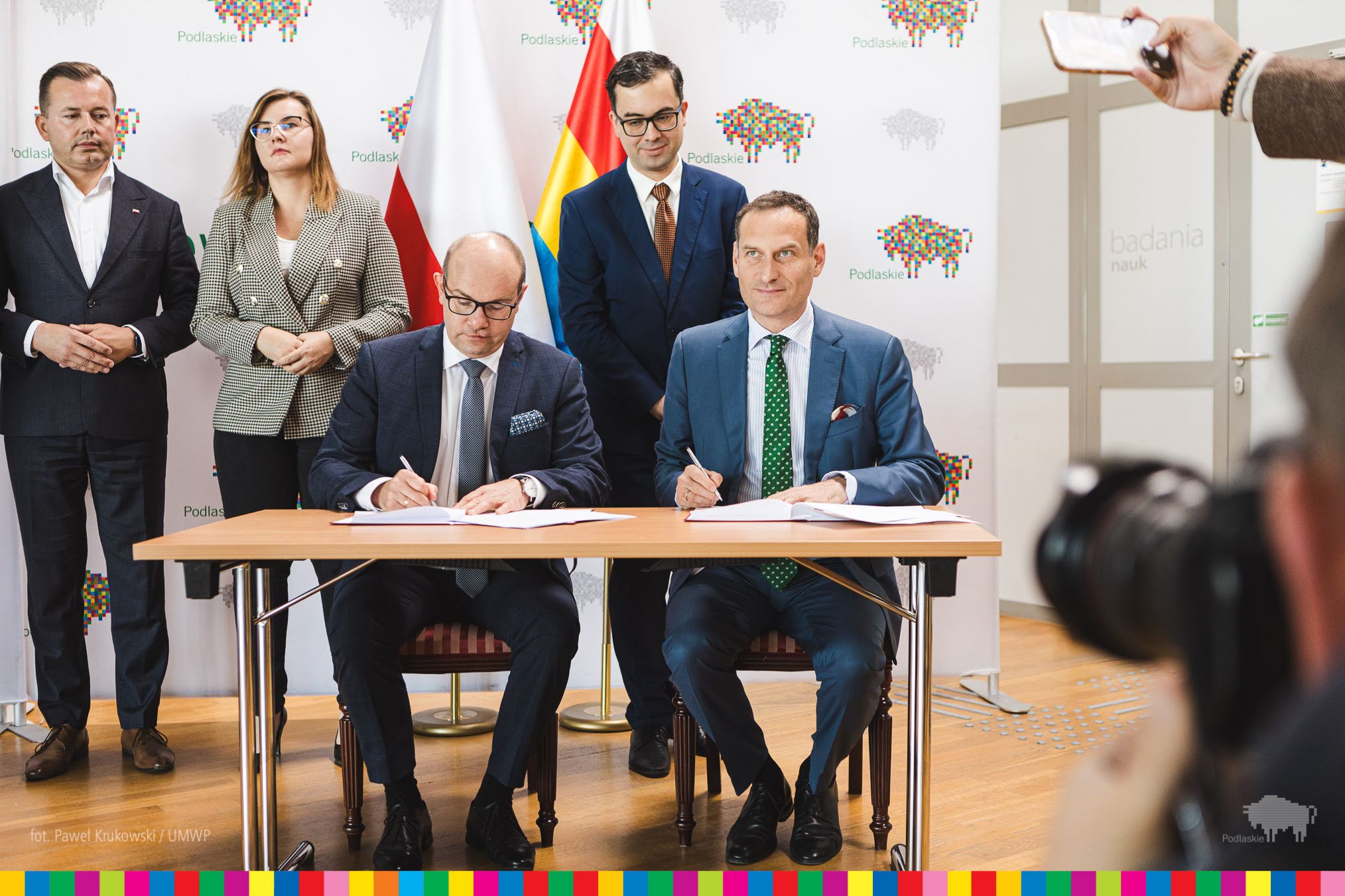 Dwóch mężczyzn siedzą przy stole i podpisuje dokumenty