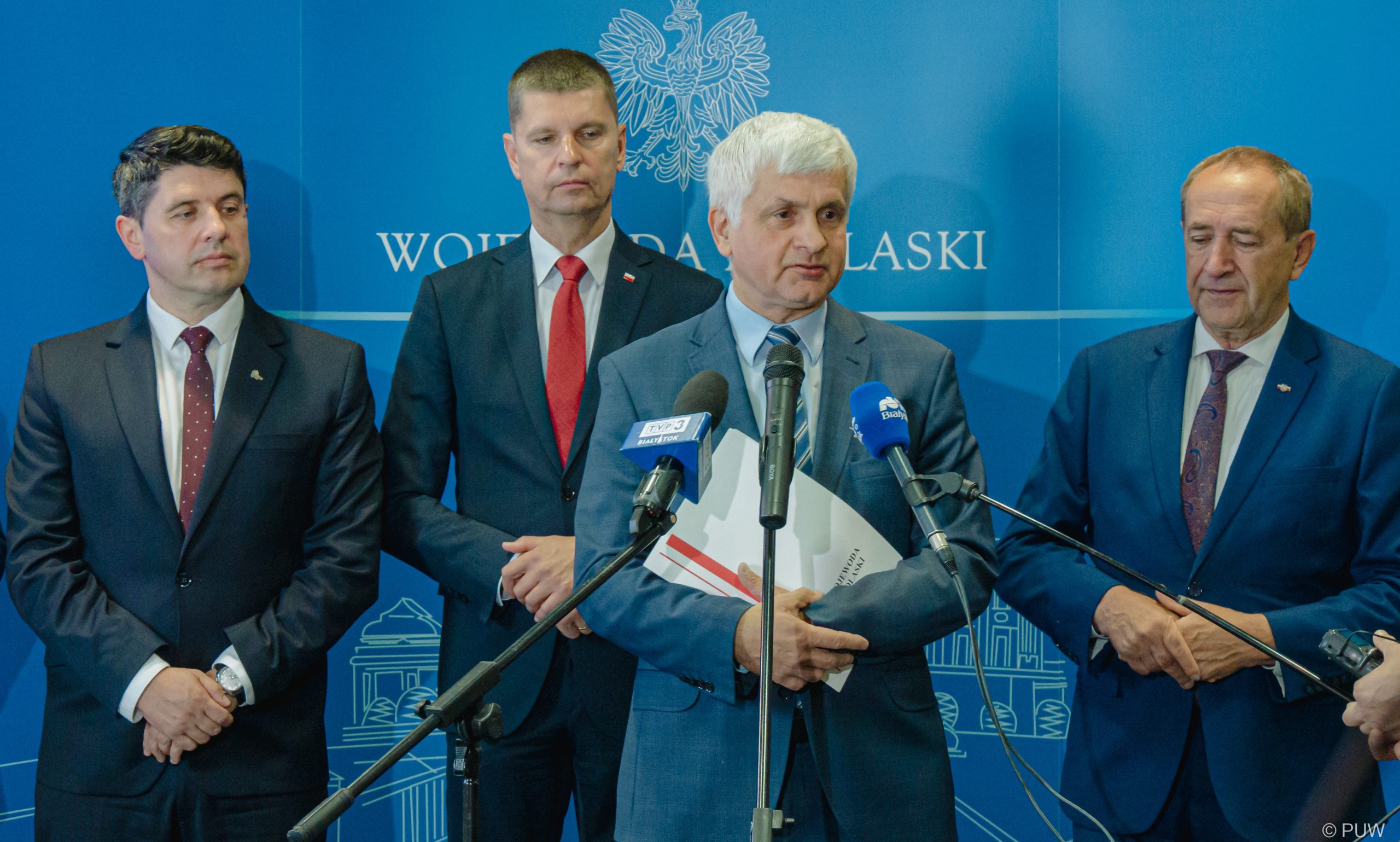 Mężczyźni stoją przed mikrofonem.