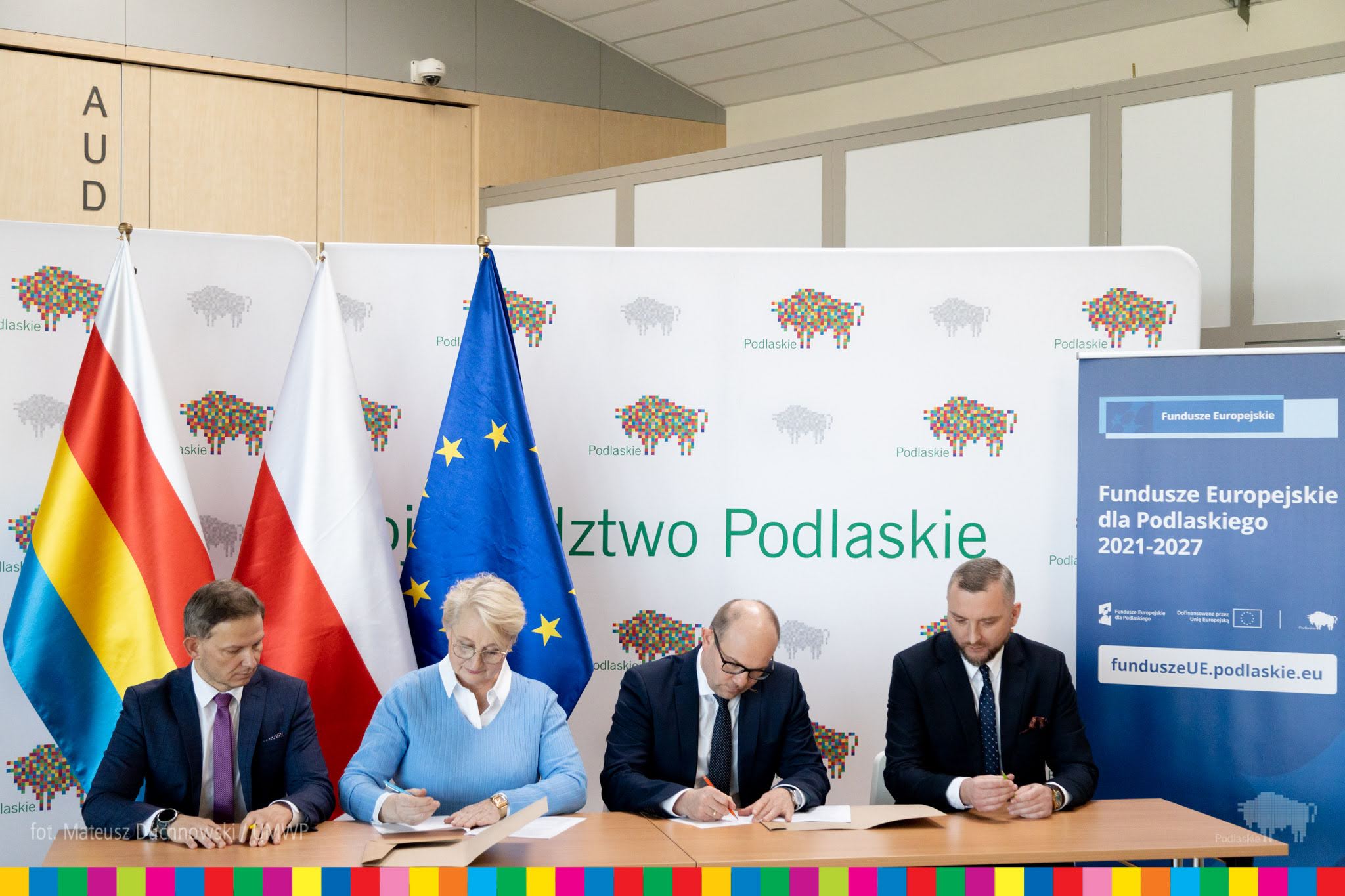 Cztery osoby podpisują dokumenty przy stole.