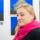 Kobieta na tle obrazów wiszących na ścianie.