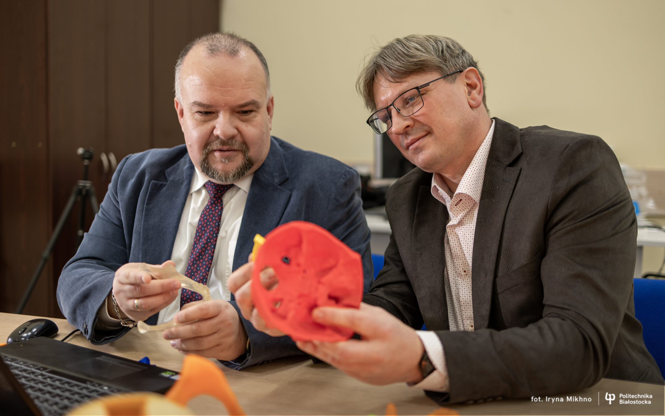 Dwóch mężczyzn trzyma czaszkę wydrukowaną na drukarce 3D
