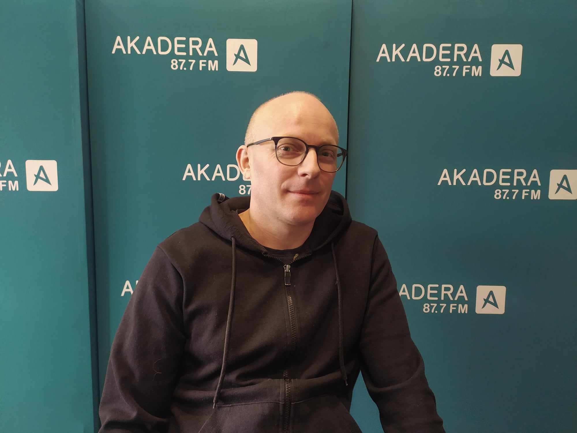 Mężczyzna na firmowej ściance promocyjnej.
