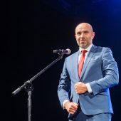 Mężczyzna przed mikrofonem na scenie.