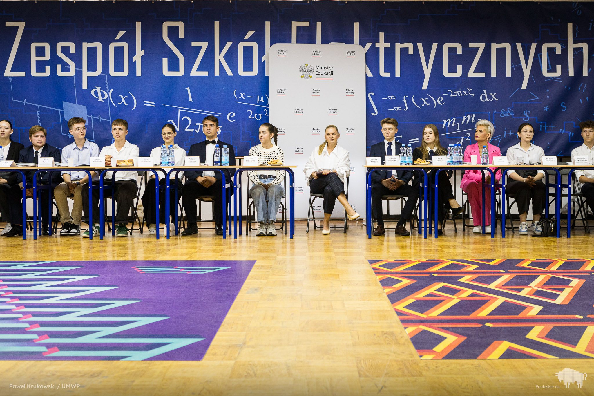 Uczniowie siedzą na apelu.