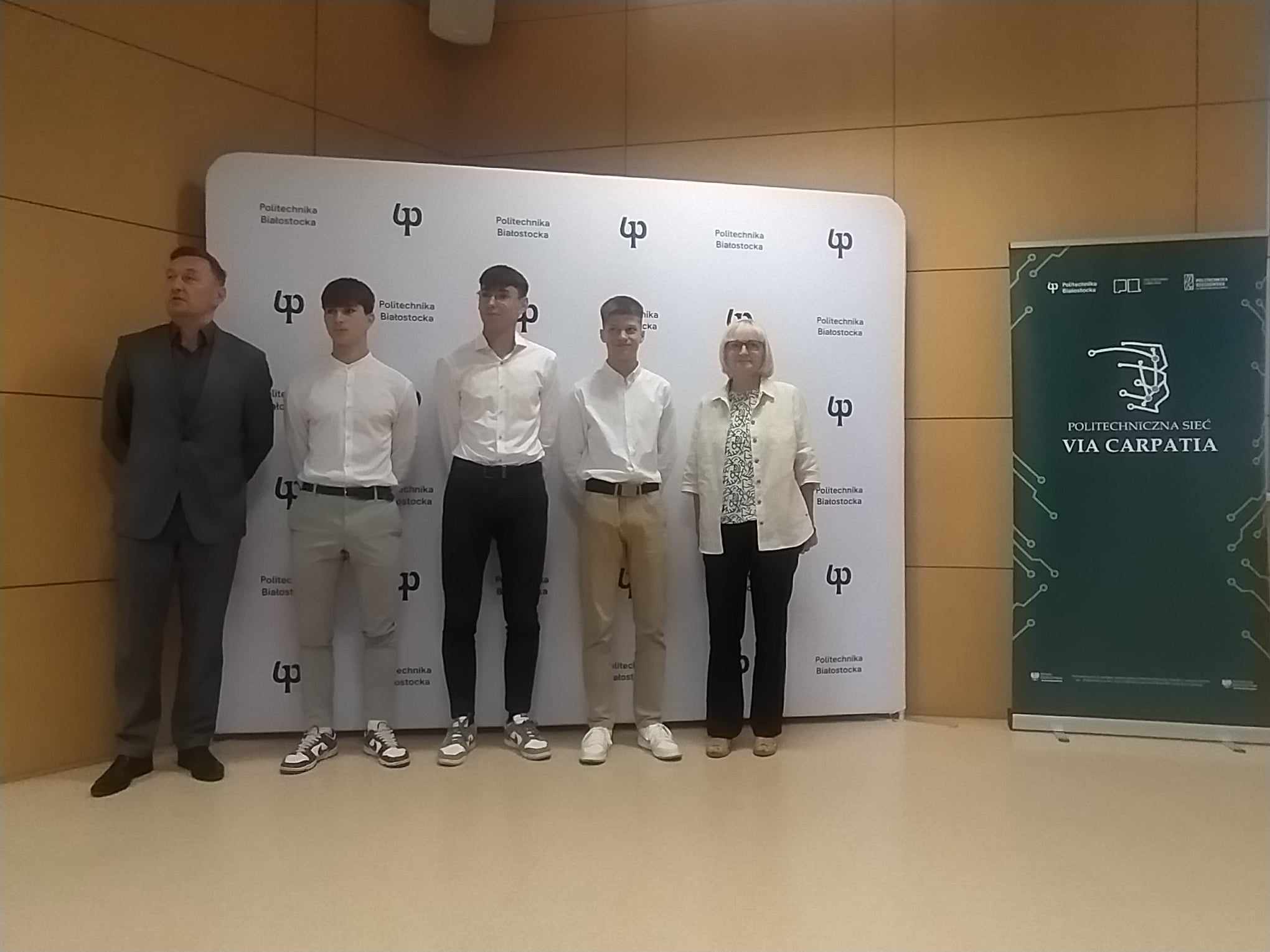 Trzech licealistów i dwie osoby dorosłe stoją na scenie.