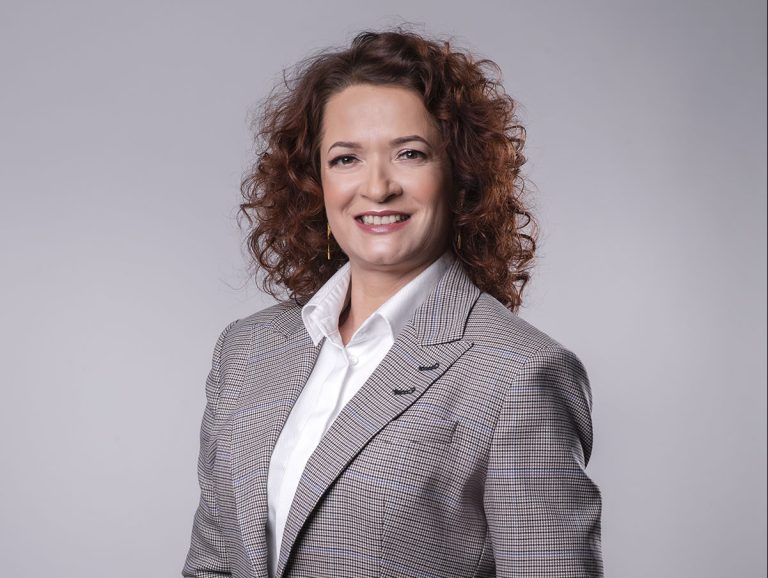 Pani rektor w szarej marynarce uśmiecha się