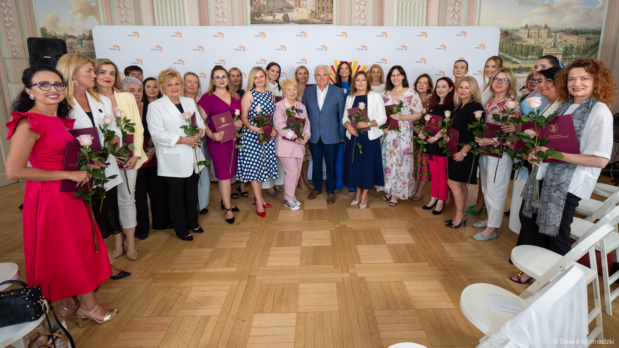 Eleganckie ubrane kobiety pozują do zdjęcia grupowego.