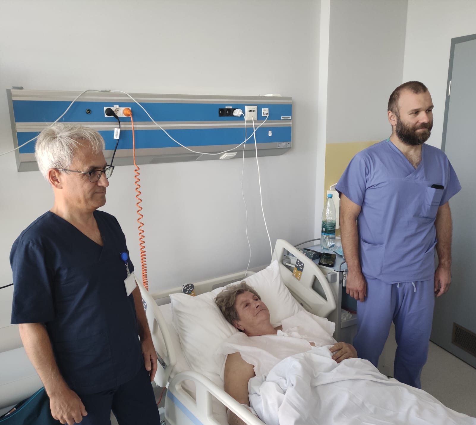 Chirurdzy razem ze swoją pacjentką pozują do zdjęcia po udanej operacji.