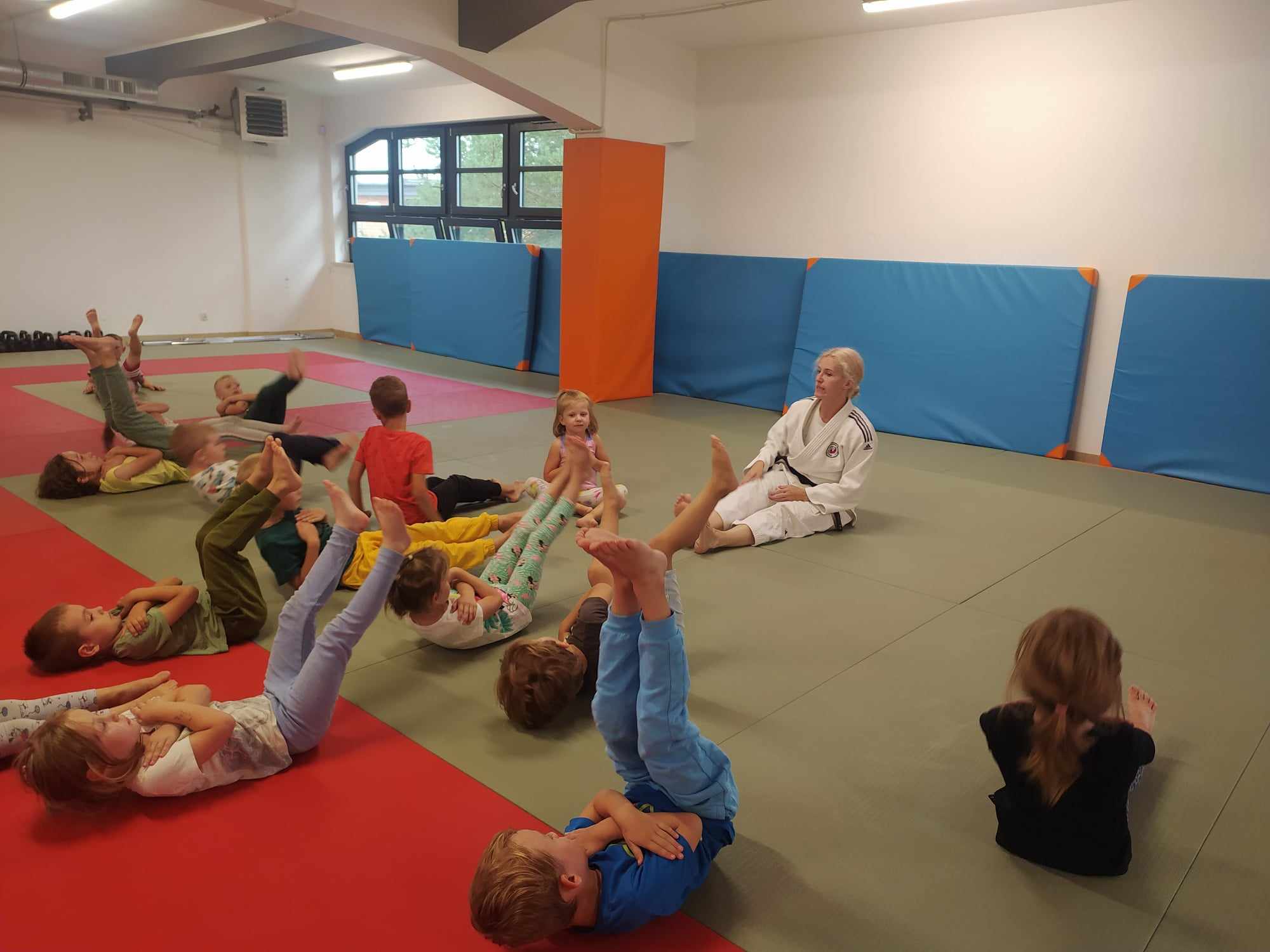 Trenerka w judoce na macie z dziećmi.