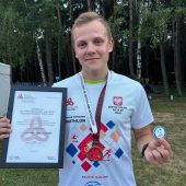 Mężczyzna trzyma dyplom i medal.