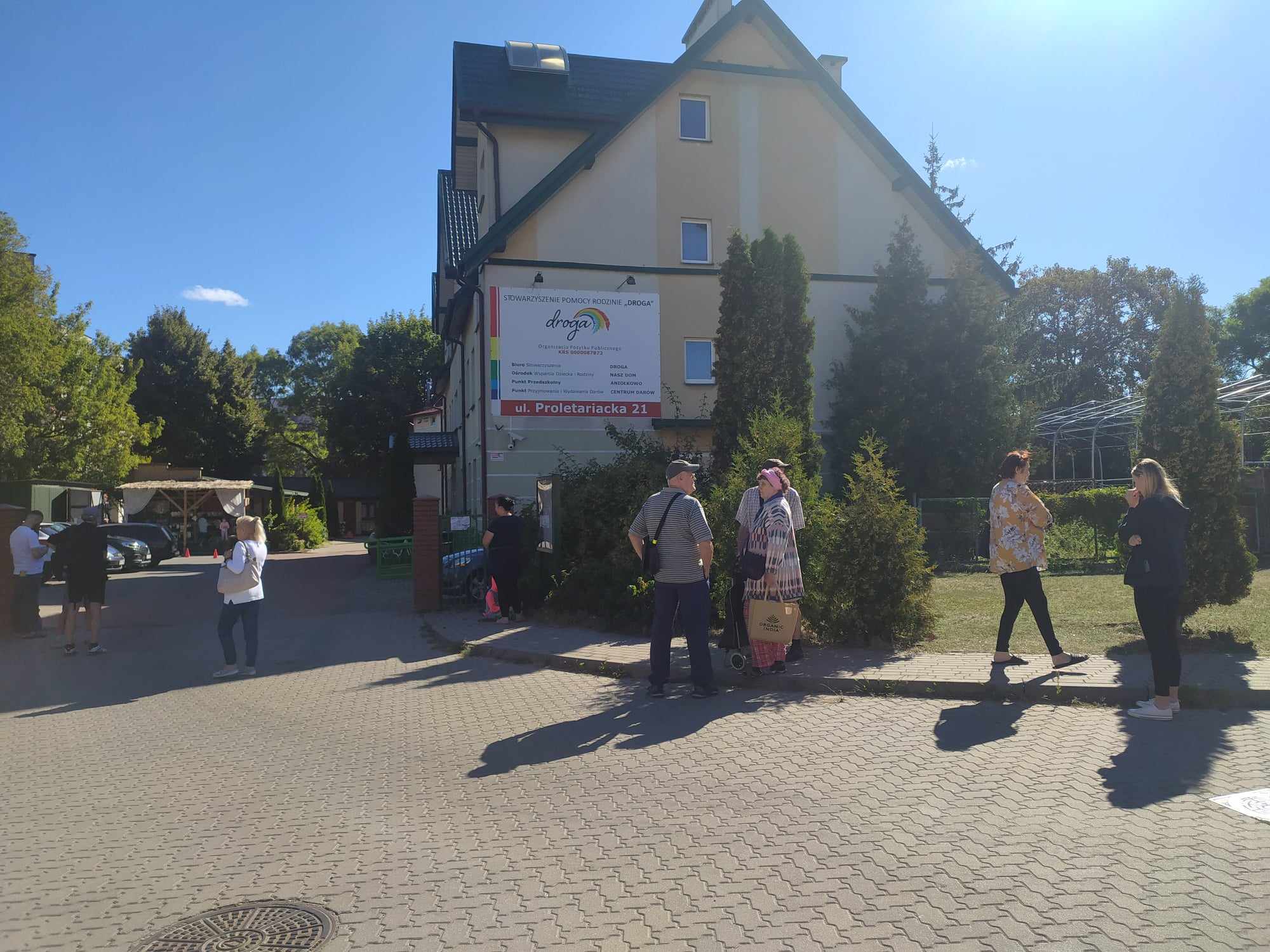 Ludzie czekają w kolejce przed budynkiem.