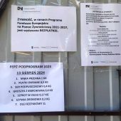 Kartki z informacjami wiszą na blasze budynku.