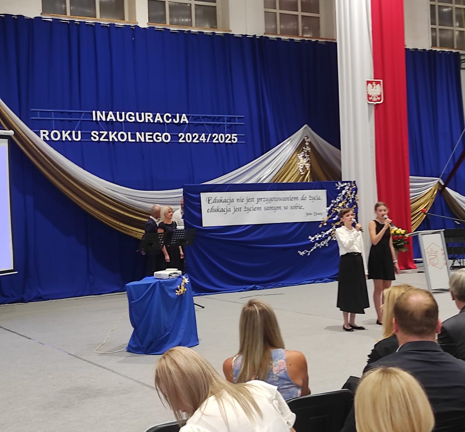 Dziewczynki śpiewają przed publicznością podczas uroczystej inauguracji roku szkolnego.