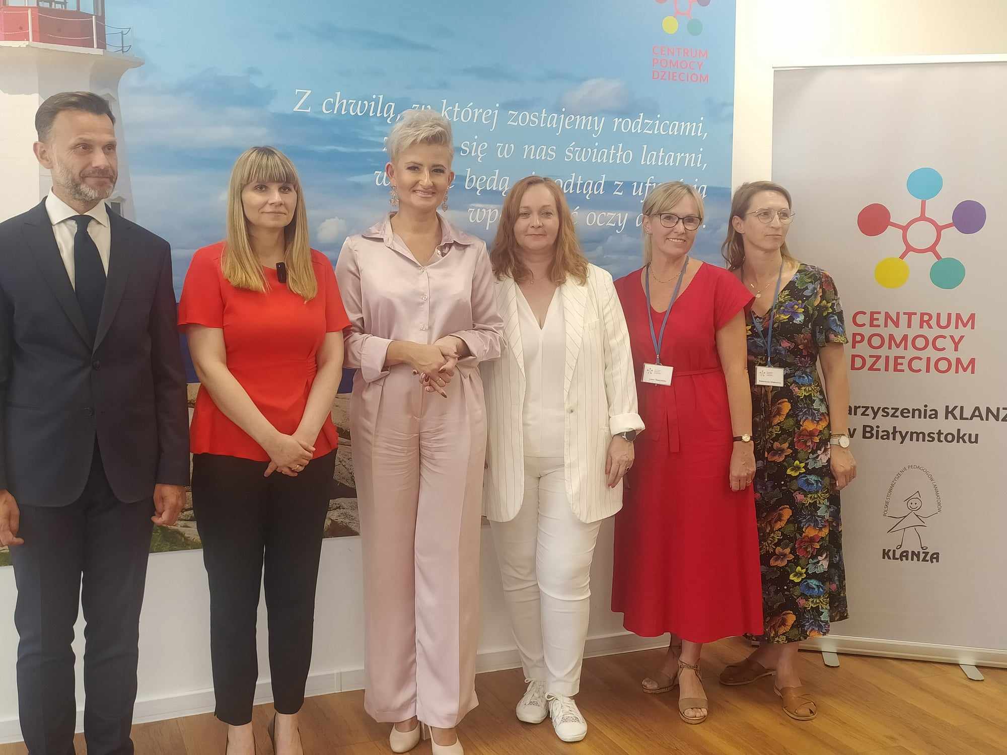 Ludzie pozują do zdjęcia pod ścianą.