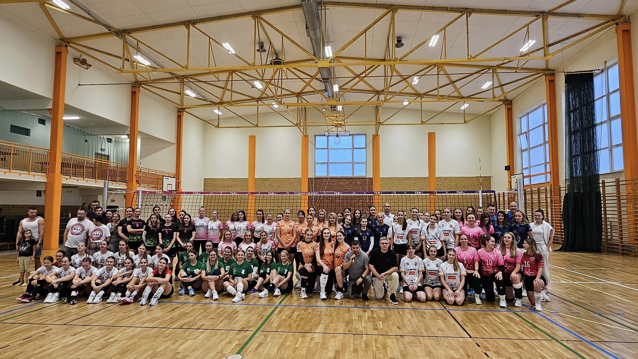 Siatkarki pozują na hali sportowej.