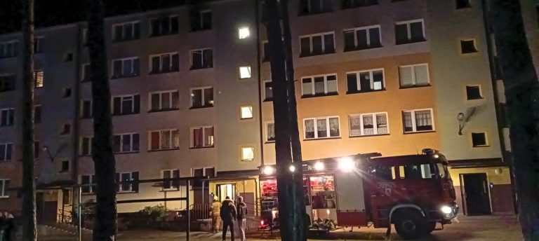 Wóz strażacki stoi w nocy na przed blokiem