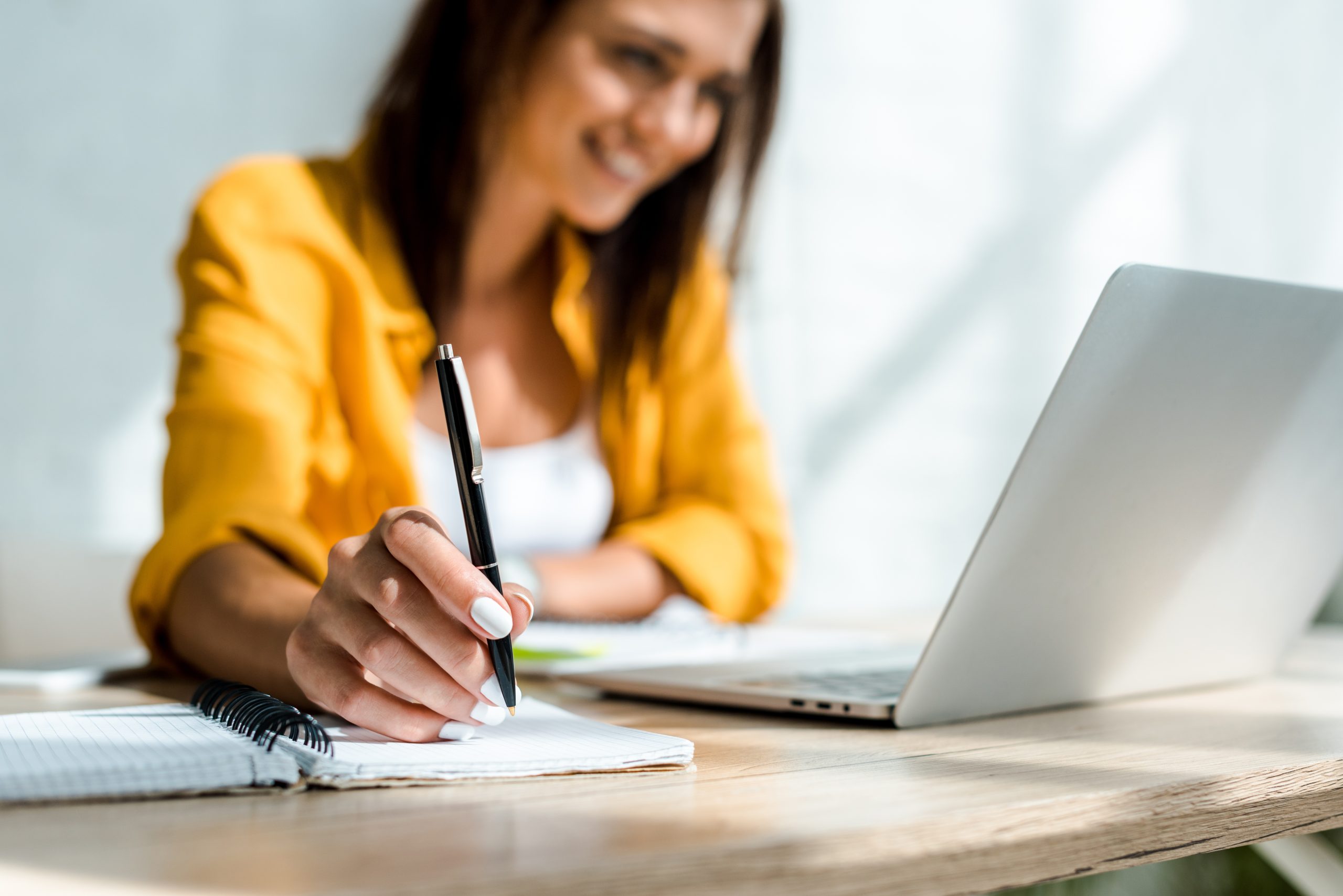 selective focus of freelancer writing and working with laptop in home office