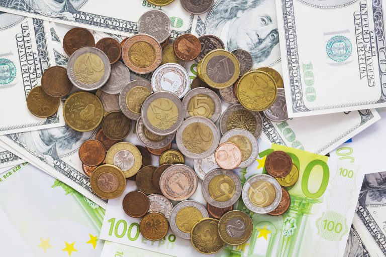 drobne bilony leżące na papierowych banknotach w różnych walutach
